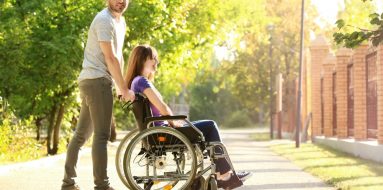 Young woman on a wheelchair with her partner enjoying the sun outdoors — Disability Support Services in Maitland, NSW