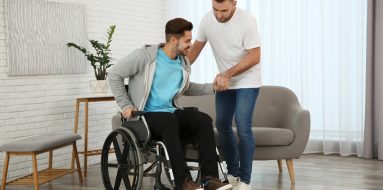 Man helping another man to stand up from the wheelchair — Disability Support Services in Gawler, SA