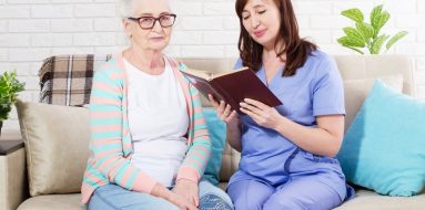 Nurse reading a book to an elderly woman with glasses — Disability Support Services in Byron Bay, NSW
