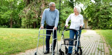 Elderly couple enjoying their stroll in a park while using their walkers — Disability Support Services in Maitland, NSW