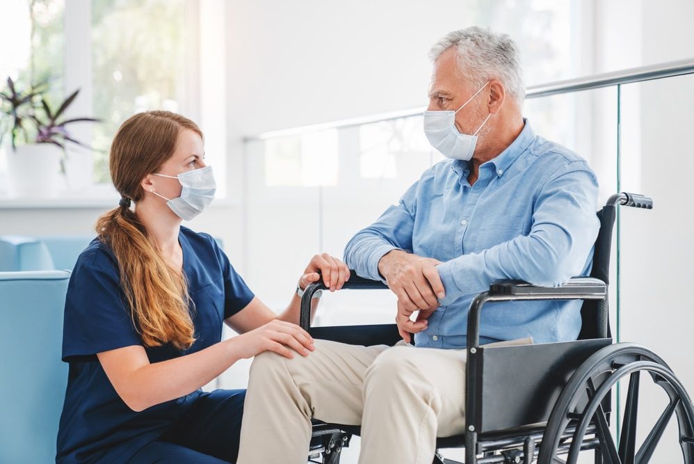 Nurse talking to an elderly man while wearing their masks on — Disability Support Services in Maitland, NSW