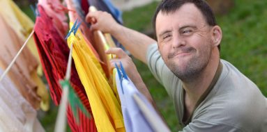 Man With Down Syndrome Hanging Clothes — Disability Support Services in Gold Coast, QLD